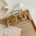 Dettaglio di una pinza per capelli ondulata da 14cm effetto marmo su vassoio di legno - Giallo Pelle di Serpente