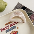 Detail of a semi-circular marble pattern hair claw with a small metal JD logo accent - Shell White