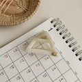 Close-up of cream acetate triangle hair claw clip with gold spring and metal emblem - Beige Stripes