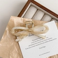 Close-up of cream acetate bow hair claw with pearl texture and golden YD emblem - Beige Khaki