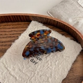 Detalle de la pinza de acetato con patrón de carey y texto dorado de la marca - Marrón Azul Lago