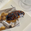 Detailed close-up of amber and blue tortoiseshell hair clip on a magazine - Lake Blue Coffee