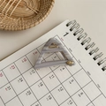 Detail view of triangular hair claw clip with grey-purple marble texture and gold logo - Grey Stripe