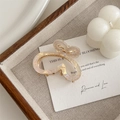 Detail of a gradient pearlescent butterfly hair claw clip with golden metal base on tray - White