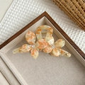 Dettaglio del fermaglio a fiori in acetato con texture ambrata e strass scintillanti - Arancione Floreale