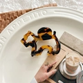 Detailed view of the tortoiseshell acetate puppy-shaped hair claw clip on a stylish dish - Dark Leopard Print