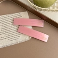 Dettaglio di fermagli per capelli in acetato rosa con scritta dorata su tessuto - Stile Rosa Lucido