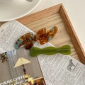 Dettaglio di fermaglio in resina tartarugata e forcina a onde verde su sfondo retro - Set Tartarugato E Verde Oliva / Marrone Blu Lago