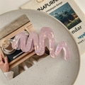Close-up of a pearlescent pink wavy hair claw clip on a stylish decorative tray - Iridescent Purple (11cm)