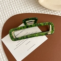 Vista macro della molletta per capelli in acetato verde marmorizzato su una carta - Verde Smeraldo