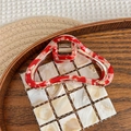 Macro detail of tortoiseshell acetate cloud hair claw clip with golden metal spring - Red