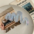 Iridescent translucent blue wave hair claw clip displayed on a marble tray with books - Iridescent Blue-Gray (11cm)