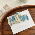 Detail der blau-beigen marmorierten gewellten Haarklammer mit kleinem goldenem Metalllogo - Blau-Weiß