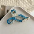 Detailed macro shot of marble textured blue and white bow hair claw on ceramic tray - Blue White