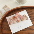 Detail einer gewellten Haarklammer aus Acetat in Pink mit goldener V-Metallverzierung - Verlauf Rosa Orange