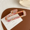 Detailed close-up of a pink marble acetate hair claw clip with golden metal spring - Floral Pink