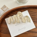 Detail der gewellten Haarklammer aus Acetat mit holografischem Finish und Gold-Logo - Irisierendes Creme
