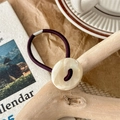Detailed shot of an elastic hair tie featuring a large marble-textured resin button detail - Off White