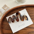 Macro view of French wavy tortoiseshell hair claw clip on a stylish decorative tray - Tortoise Shell