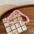 Detail of coral marble acetate hair claw with gold metal hinge and carved logo - Warm Pink