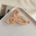 Macro detail of peach acetate hair claw clip featuring golden YD logo and marbled texture - Light Orange
