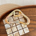 Detail of large acetate hair claw clip with colorful marble texture and gold spring - AB Color