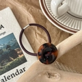 Close-up of tortoise shell button hair tie on rustic wooden surface with retro props - Caramel Leopard