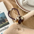 Detailed shot of an elastic hair tie featuring an amber tortoiseshell resin ring decoration - Brown Cow Print