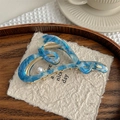 Detail view of acetate heart claw clip with blue marble pattern and elegant pearl accent - Blue