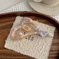Macro detail of acetate heart hair claw with iridescent texture and pearl accent - Pink Purple
