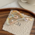 Detail of marble acetate heart hair claw with gold frame and pearl accent on paper - Rainbow