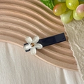 Dettaglio di un fermaglio blu con fiore bianco perlato su un vassoio di legno - Fiore Bianco Base Blu