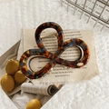 Detail of tortoise shell claw clip with amber pattern and gold metal spring on fabric - Lake Blue Coffee