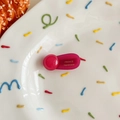 Macro-opname van handgemaakte roze haarklem van acryl met gouden letters op een bordje - Rozerood