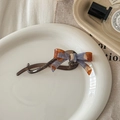 Détail du nœud papillon en acétate avec logo France Handmade doré sur une assiette blanche - Bleu Brun Beige