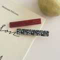 Detailansicht eleganter Haarklammern aus Acetat mit Marmor- und Punktmuster auf einem Buch - Rote Punkte + Schwarze Punkte