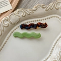 Detailed macro view of wave-shaped acetate hair clips in tortoiseshell and green finish - Lake Blue Coffee And Green