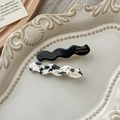 Detail of wavy acetate hair clips in black and marble patterns on a ceramic tray - Cow Pattern And Black