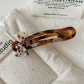 Detail van haarclip met luipaardprint en gouden ster hanger op een beige tas - 3D Strik Stijl (stars) / Lichte Luipaardprint