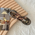 Detail of a brown acrylic hair claw with leopard print cat on a wooden tray - Spotted Cat