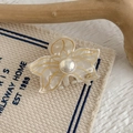 Detailed close-up of an elegant acetate flower hair claw with a pearl and golden edges - Shell White