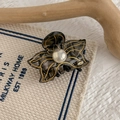 Close-up of a smoky grey acetate flower hair claw with gold edges and pearl detail - Deep Black