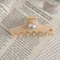 Close-up of cream hair claw clip with large pearl and gold clover detail on vintage books - Clover Metal Logo (Beige) / Off White