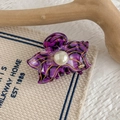 Detail view of purple flower hair claw featuring acetic acid marble texture and a large pearl - Charm Purple