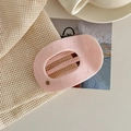 Detail showing pink marble texture acetate hair claw clip with a gold MY logo on a neutral bag - Light Pink