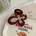 Detailed close-up of dark red flower hair claw clip on decorative cream tray - Angola Red