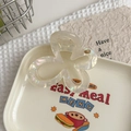 Macro shot of iridescent flower claw clip with YD metal logo on a cream background - Mermaid White