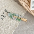 Detailed close-up of marble pattern acetate hair clip with golden metal clip on paper - Pink Green Floral