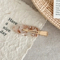 Detail of amber acetate duckbill hair clip with golden metal fastener on textured paper - Milk Brown Pattern