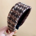 Close-up detail of a wide houndstooth plaid knitted headband with warm wool texture - Brown